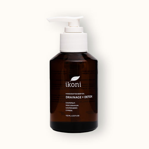 A brown glass bottle with white pump of ikoni Drainage + Detox body oil.