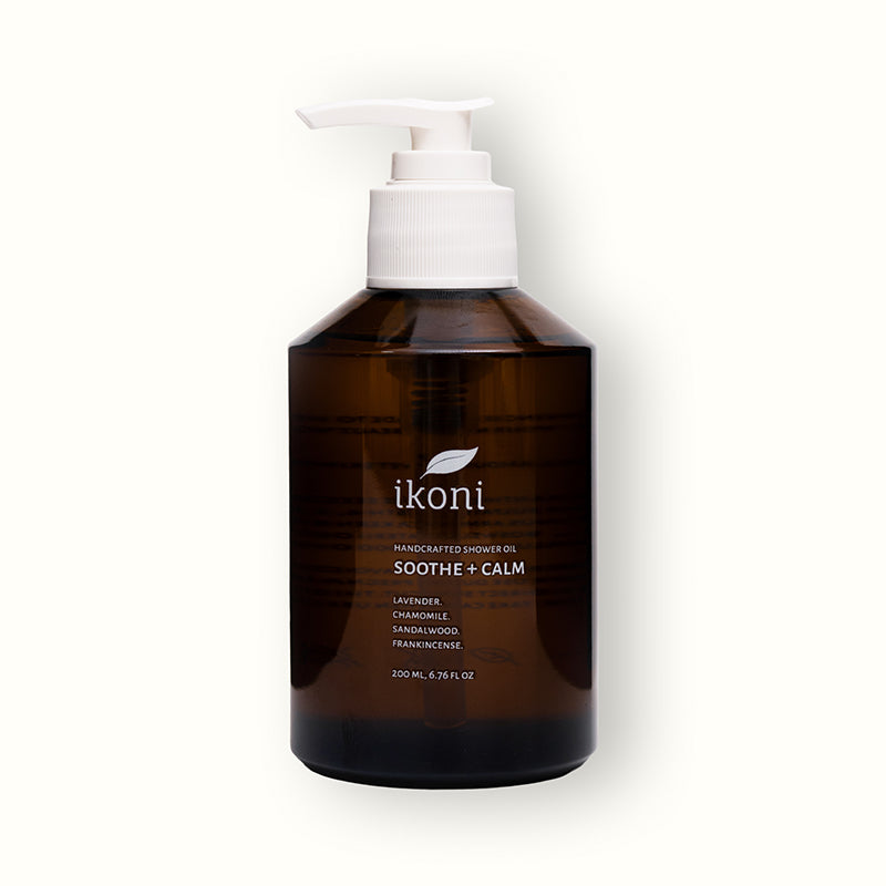 A brown glass bottle with white pump of ikoni Sooth + Calm shower oil.